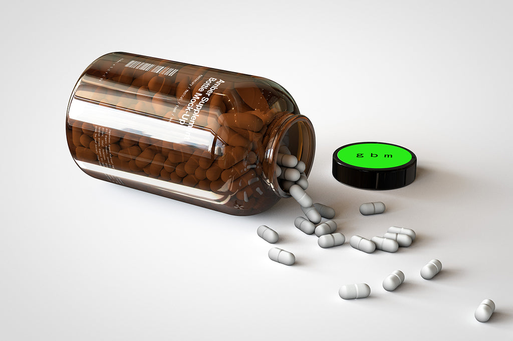 A shiny glass amber supplement/vitamins bottle mock-up full of pills on a white surface with an editable label on the front of the bottle and lid turned on its side with the pills spilling out onto the table